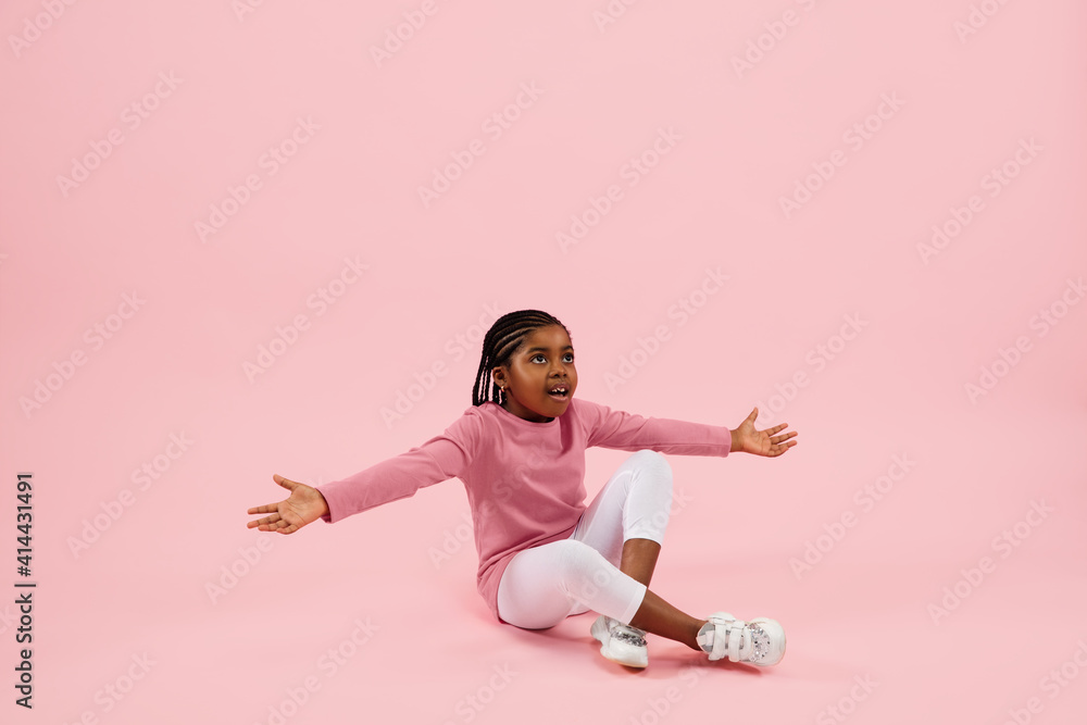 Pointing, showing. Childhood and dream about big and famous future. Pretty little girl isolated on coral pink studio background. Dreams, imagination, education, facial expression, emotions concept. Pointing, showing. Childhood and dream about big and famous future. Pretty little girl isolated on coral pink studio background. Dreams, imagination, education, facial expression, emotions concept.