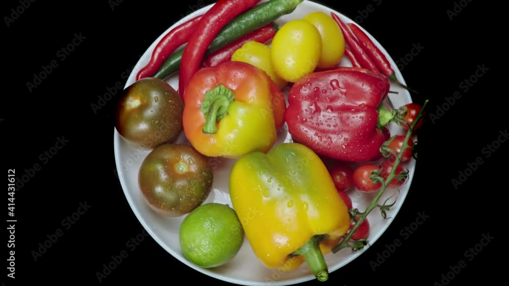 Composition of vegetables, rotation of a white plate with pepper and tomatoes Composition of vegetables, rotation of a white plate with pepper and tomatoes