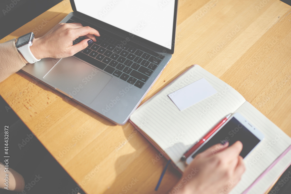 Crop unrecognizable woman using laptop and smartphone at desk Crop unrecognizable woman using laptop and smartphone at desk
