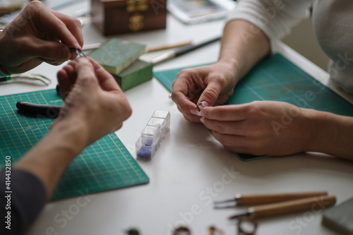 two contemporary working together in jewelry workshop. Master and apprentice. Young male assistant and female jeweler are working together at jewelry making workshop. photo