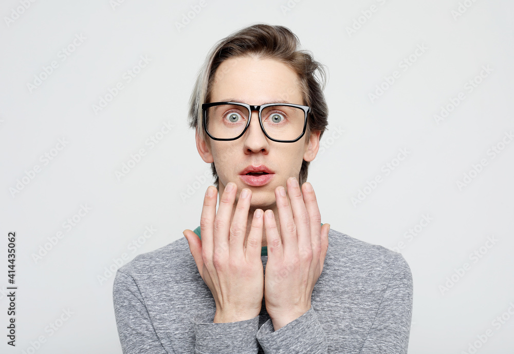 Portrait of insecure and scared handsome young man, wear glasses hold hands pressed to chest