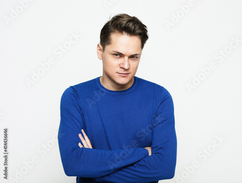 Handsome man over isolated background skeptic and nervous, disapproving expression on face with crossed arms. © Raisa Kanareva