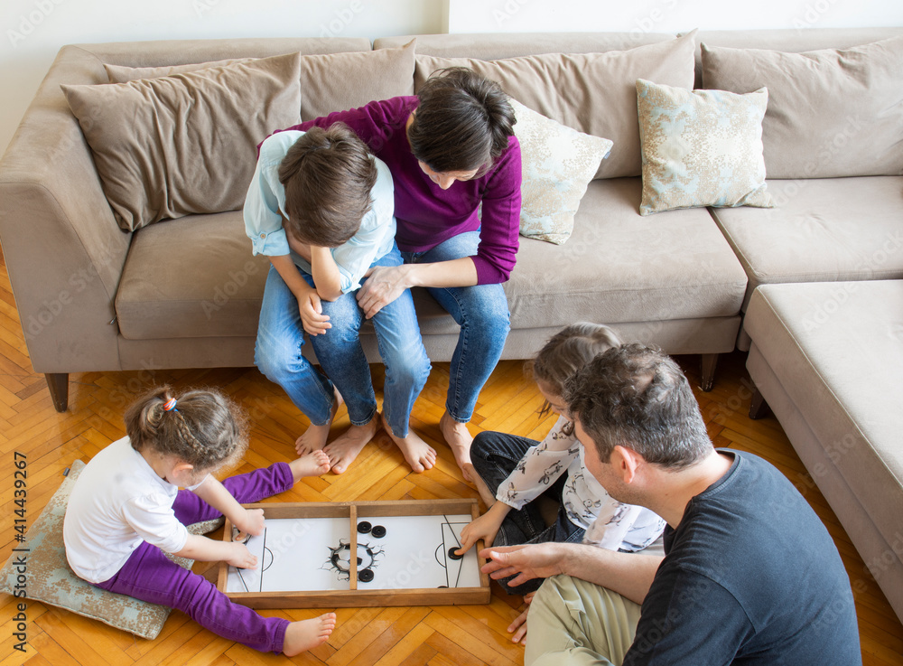 Whole Family playing game. Mother and little girl playing. Sitting on the floor in the middle of the living room 