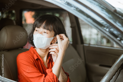 asian Woman in protective mask driving a car on road. Safe traveling.