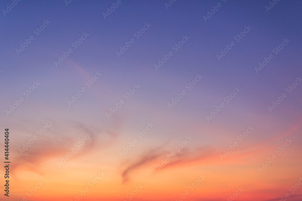 Colorful sunset sky in the evening on twilight with peaceful orange sunlight cloud fluffy and dark blue dusk sky background. 