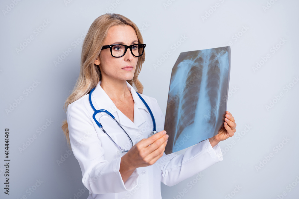 Photo of charming serious age woman therapist dressed white coat holding x-ray photo isolated grey color background Photo of charming serious age woman therapist dressed white coat holding x-ray photo isolated grey color background