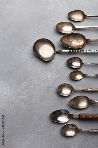 Set of various empty vintage spoons in a row on gray stone background. Top view, copy space, flat lay