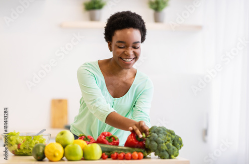 Black Lady Cooking Vegetable Meal Standing In Kitchen At Home
