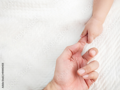 Top view of a little hand of baby  holding finger of a father hand