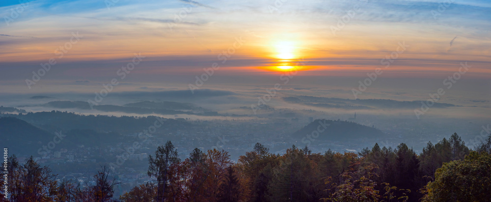 Amazing foggy sunrise over the city of Graz with Schlossberg hill and Church of the Sacred Heart of Jesus tower, in Styria region, Austria. Panoramic view from Plabutsch mountain on autumn morning. Amazing foggy sunrise over the city of Graz with Schlossberg hill and Church of the Sacred Heart of Jesus tower, in Styria region, Austria. Panoramic view from Plabutsch mountain on autumn morning.