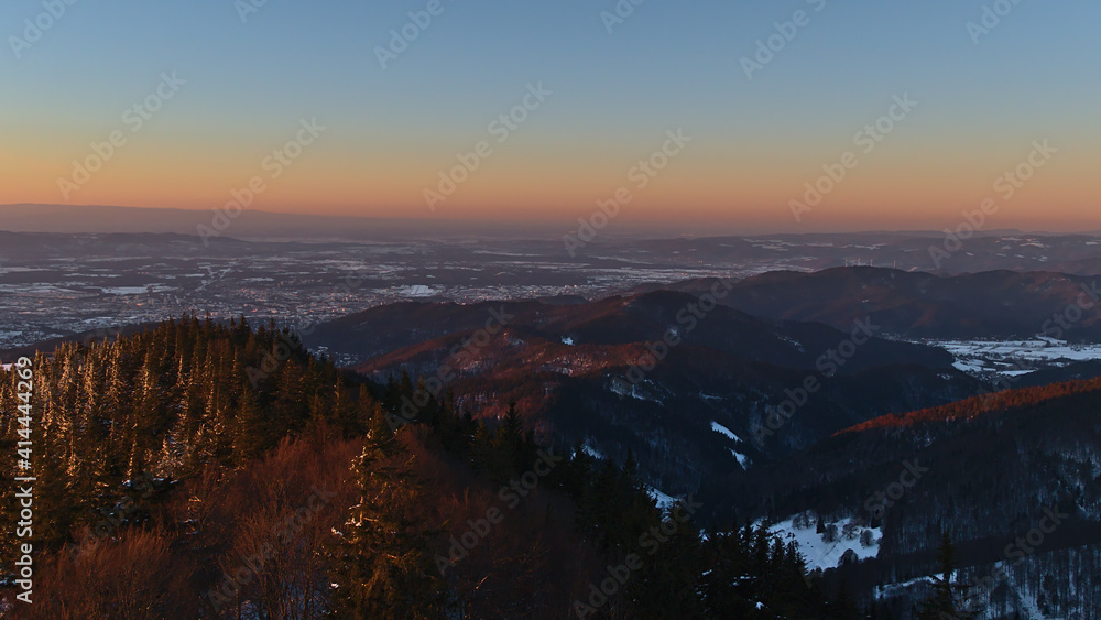 Beautiful aerial view over the foothills of Black Forest and city Freiburg im Breisgau in the evening light in winter season with snow-covered landscape and Belt of Venus (Venus's Girdle) on horizon.