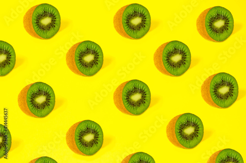 Pattern of kiwi slices on a bright yellow background with trendy sunlight. Minimum summer concept.