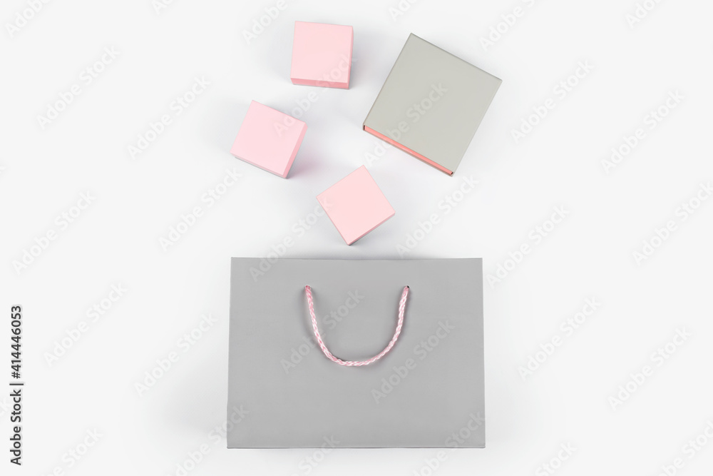 Gray paper shopping bag and pink gift boxes on light background. Shopping, sale, surprise or gift concept. Free space for text Gray paper shopping bag and pink gift boxes on light background. Shopping, sale, surprise or gift concept. Free space for text