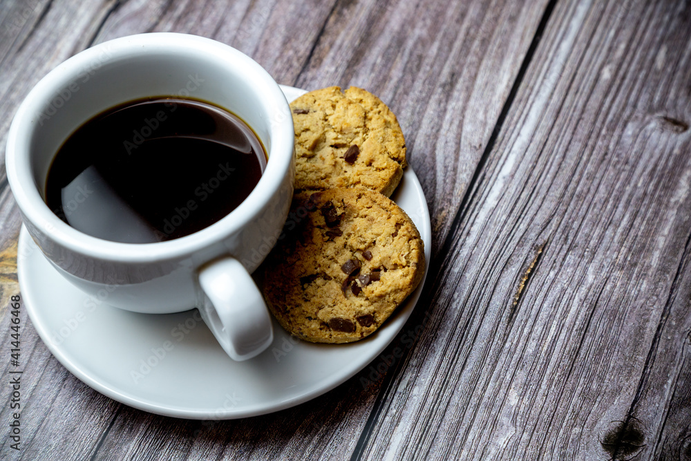 chocolate chip cookies next to a cup of coffee on a saucer on a rustic wooden table chocolate chip cookies next to a cup of coffee on a saucer on a rustic wooden table