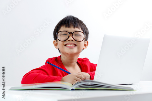 Portrait of a cute little Asian boy using a laptop at home, online, video chatting, education, E-learning concept.