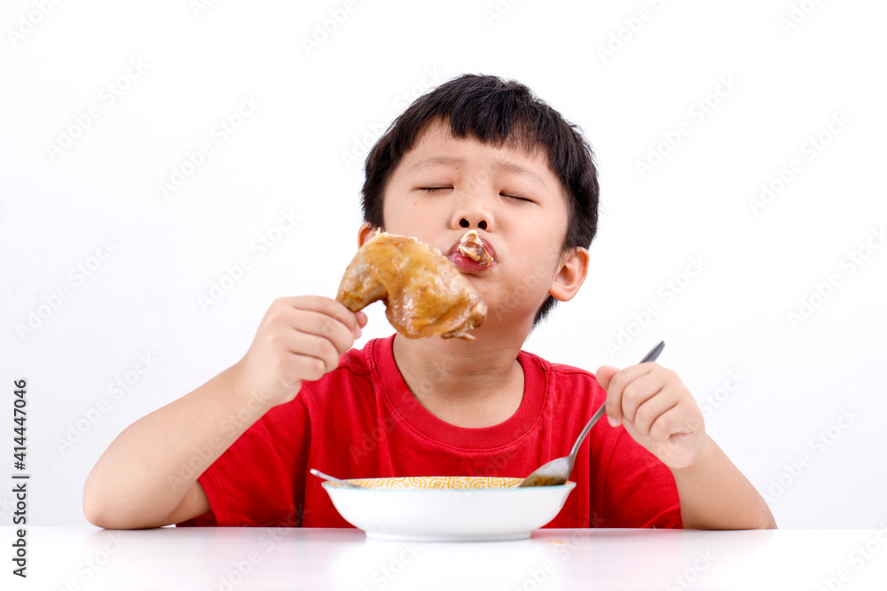 Portrait of cute little Asian boy enjoying eating chicken drumstick with noodles at home, isolated on white background. Portrait of cute little Asian boy enjoying eating chicken drumstick with noodles at home, isolated on white background.