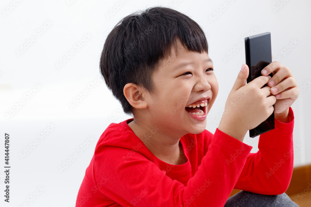 Happy little Asian boy using a smartphone at home, isolated on white background. Happy little Asian boy using a smartphone at home, isolated on white background.