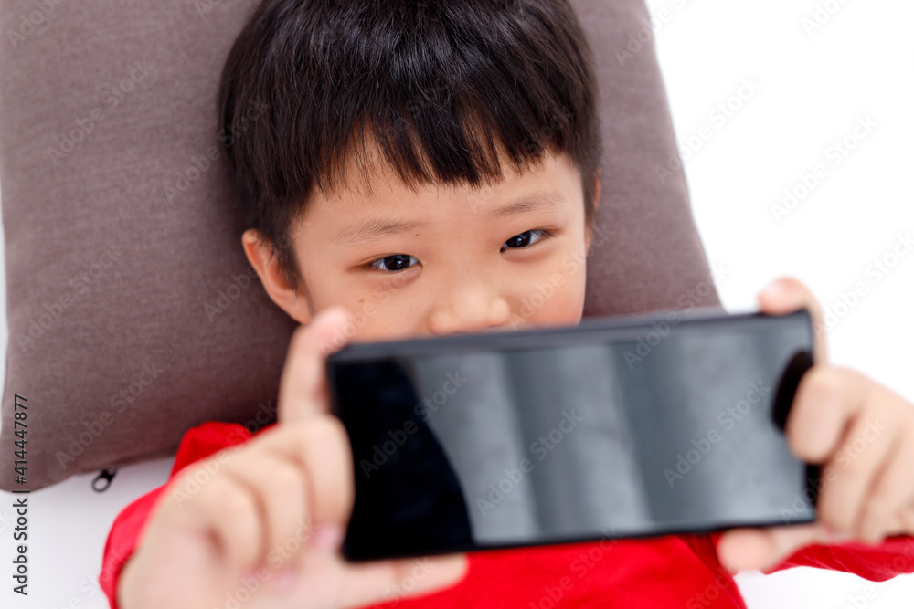 Happy little Asian boy using a smartphone at home, isolated on white background. Happy little Asian boy using a smartphone at home, isolated on white background.