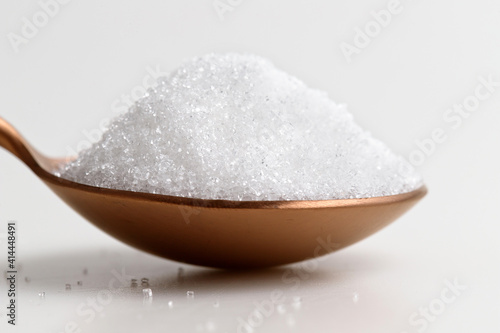 Tablespoon filled with granulated sugar on white background