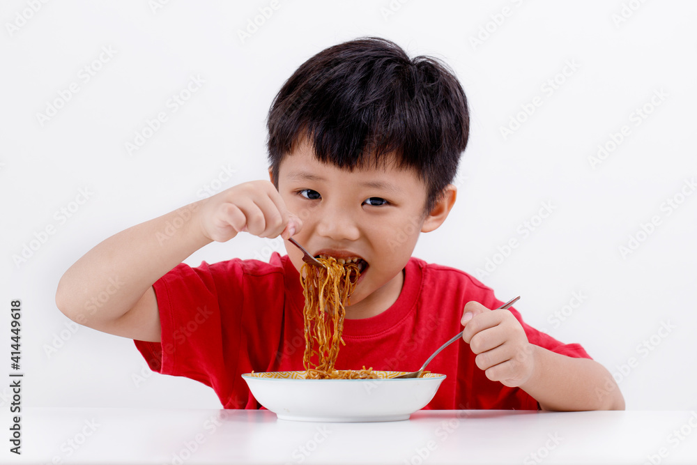 Cute little Asian boy enjoying eating noodles at home, isolated on white background Cute little Asian boy enjoying eating noodles at home, isolated on white background