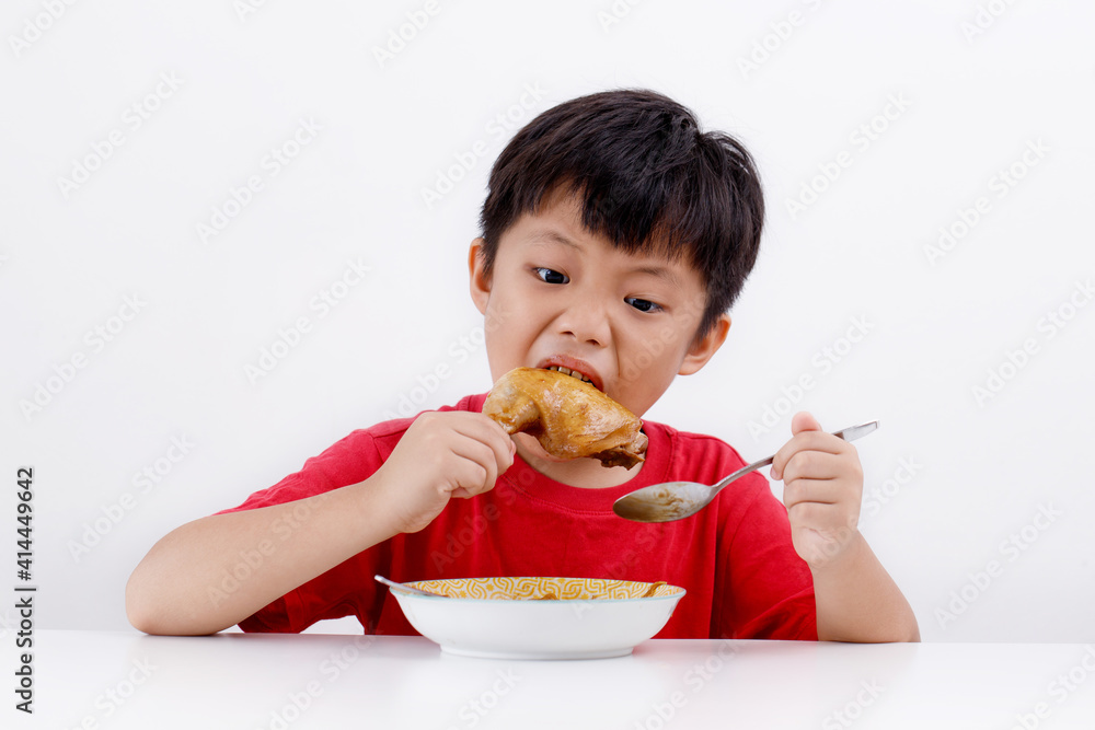 Cute little Asian boy enjoying eating chicken drumstick with noodles at home, isolated on white background Cute little Asian boy enjoying eating chicken drumstick with noodles at home, isolated on white background