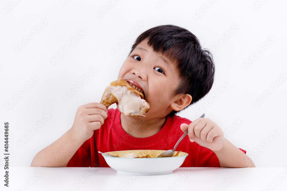 Cute little Asian boy enjoying eating chicken drumstick with noodles at home, isolated on white background Cute little Asian boy enjoying eating chicken drumstick with noodles at home, isolated on white background