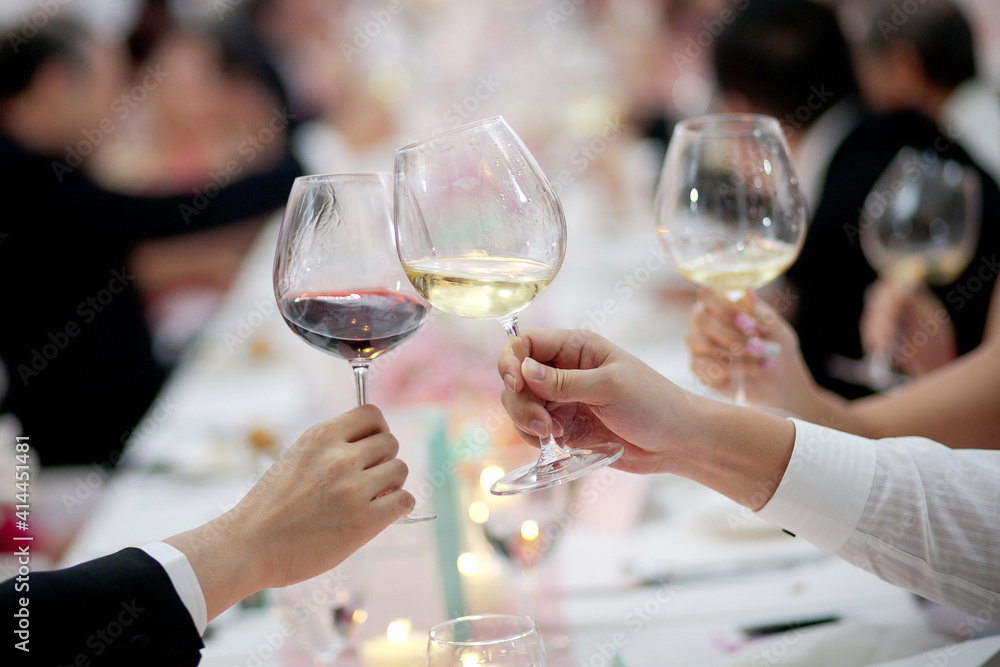 A group of unrecognizable people toasting with wine in a restaurant. A group of unrecognizable people toasting with wine in a restaurant.