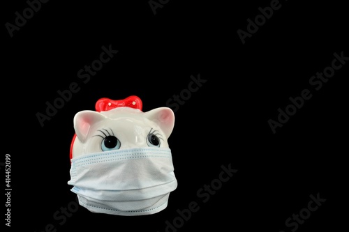 Piggy bank in a medical mask on a black background isolated close-up. The concept of the crisis in the economy and business due to the Covid pandemic