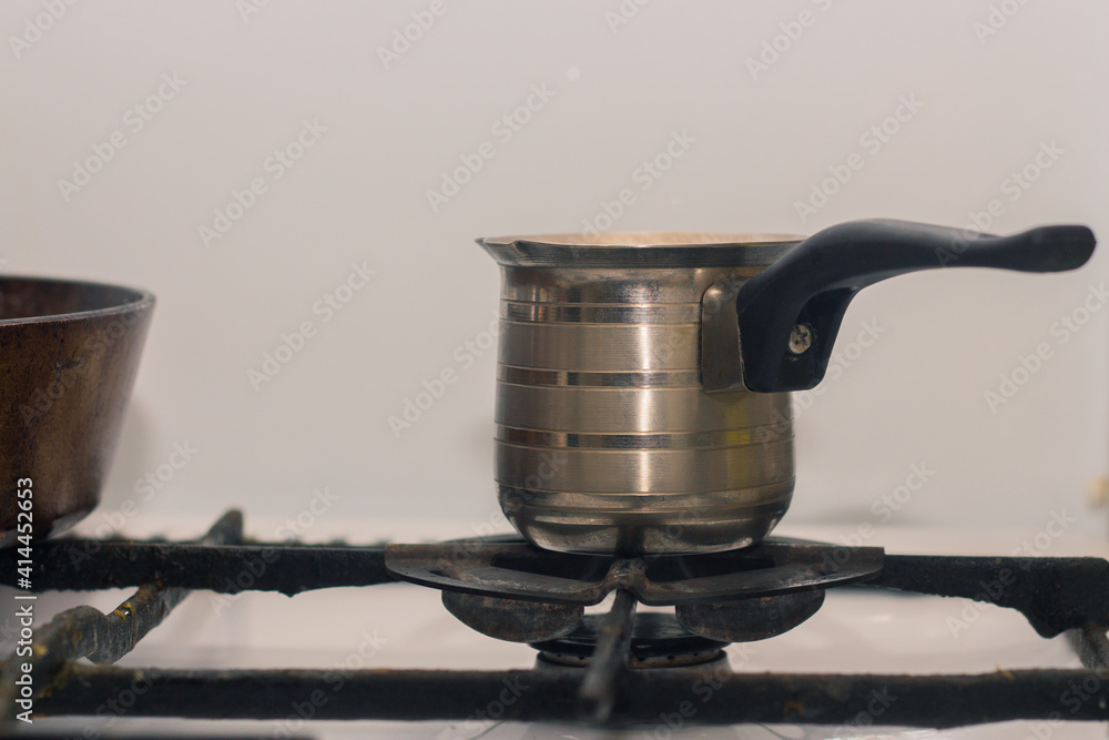 Obraz premium Hot coffee prepared in turk on a gas retro stove