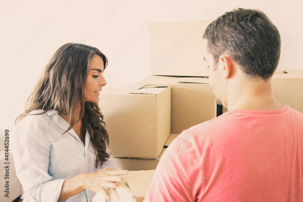 Obraz premium Man and woman carrying carton boxes among packages in new apartment. Transportation service or property buying concept