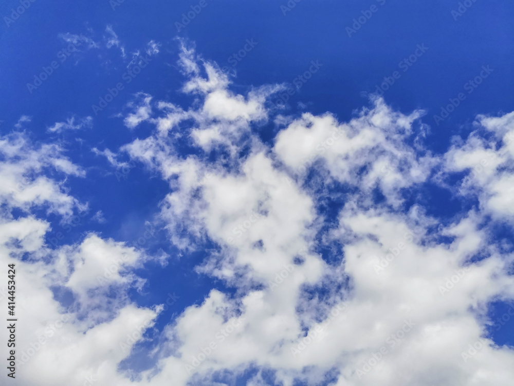 Fototapeta premium White fluffy volumetric cumulus clouds against a bright blue sky. Beautiful natural sky background. Sky backdrop for your photos