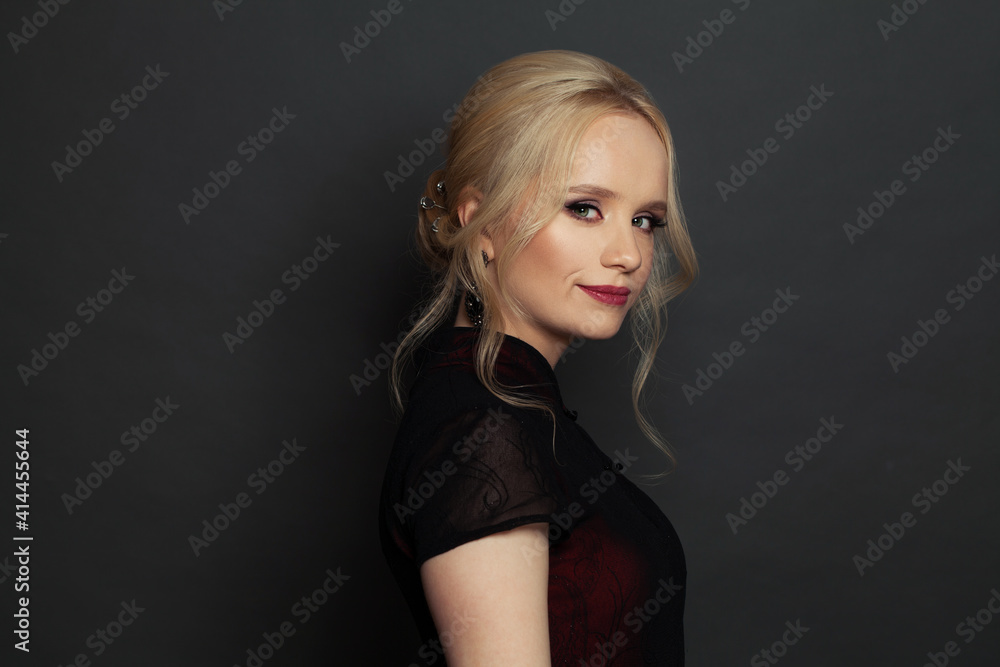 Naklejka premium Stylish young woman with blonde hair and makeup on black background