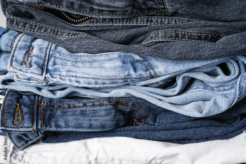 Folded jeans on gray background, close-up. Denim background Folded jeans on gray background, close-up. Denim background