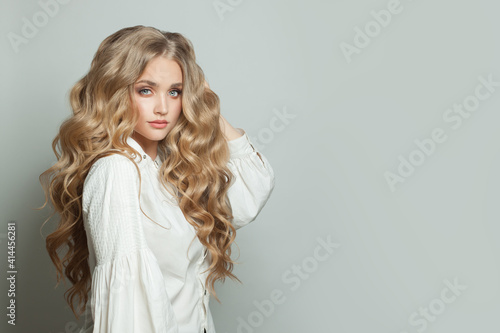 Perfect young woman with long blonde healthy curly hairdo on white background photo