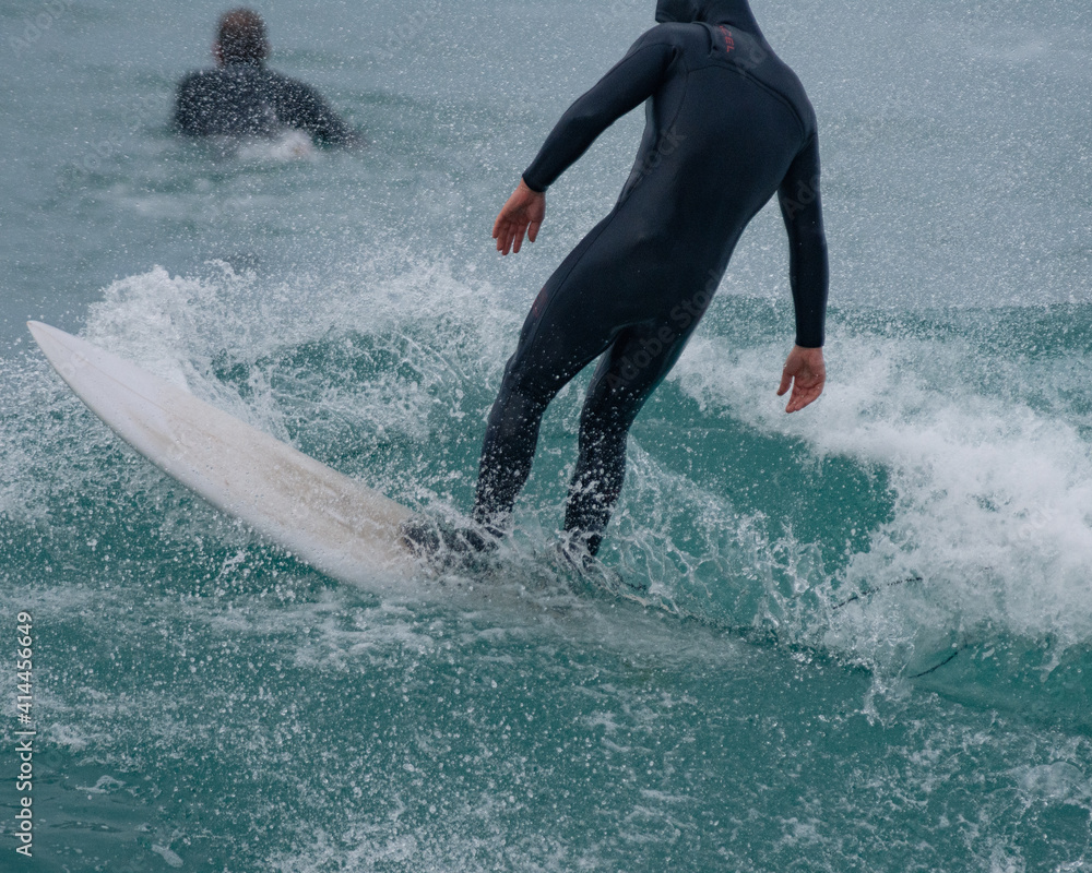 Fototapeta premium Surfer Carving and performing tricks on huge blue waves in Newquay, Cornwall - Southwest England