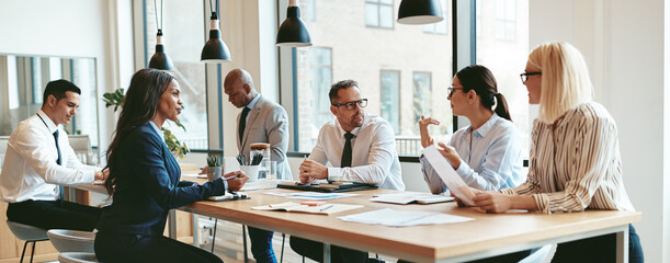 Diverse group of businesspeople talking together around an office table