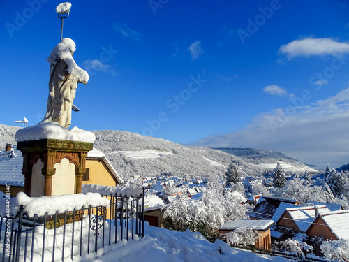Statue looking towards the Florival valley, with the villages of Buhl and Guebwiller (Alsace, France) under the snow and the forest and the mountain in the background, in good weather and blue sky