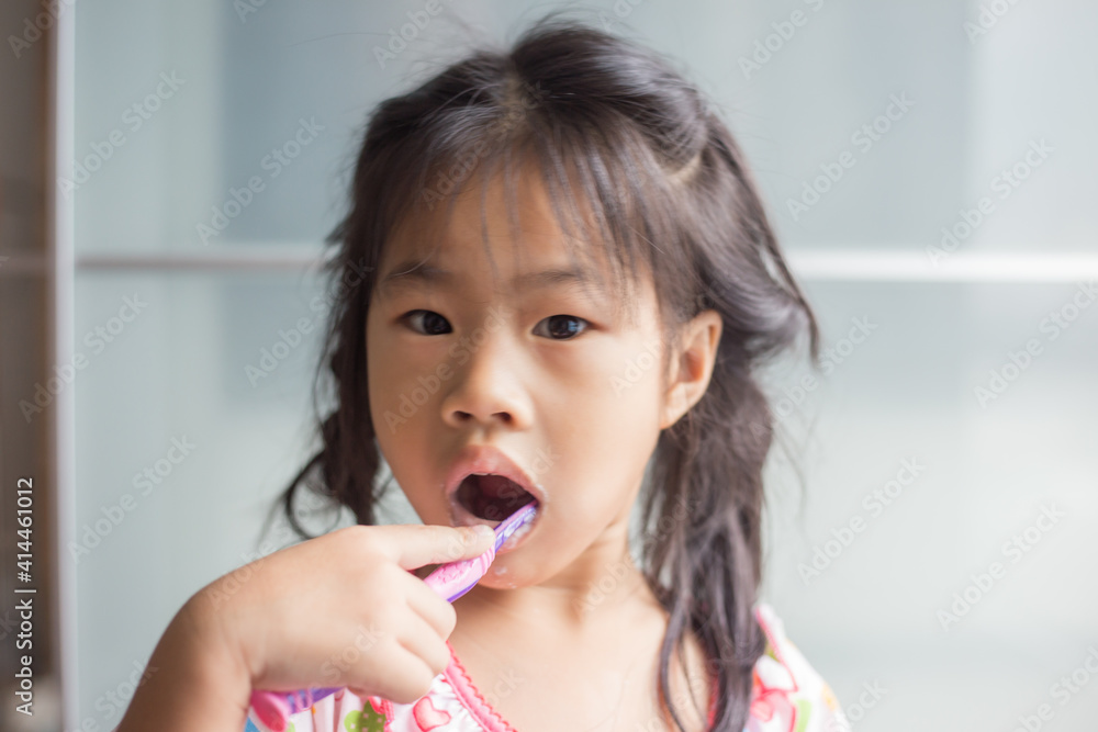 Little asian girl brushing her teeth in bathroom Little asian girl brushing her teeth in bathroom