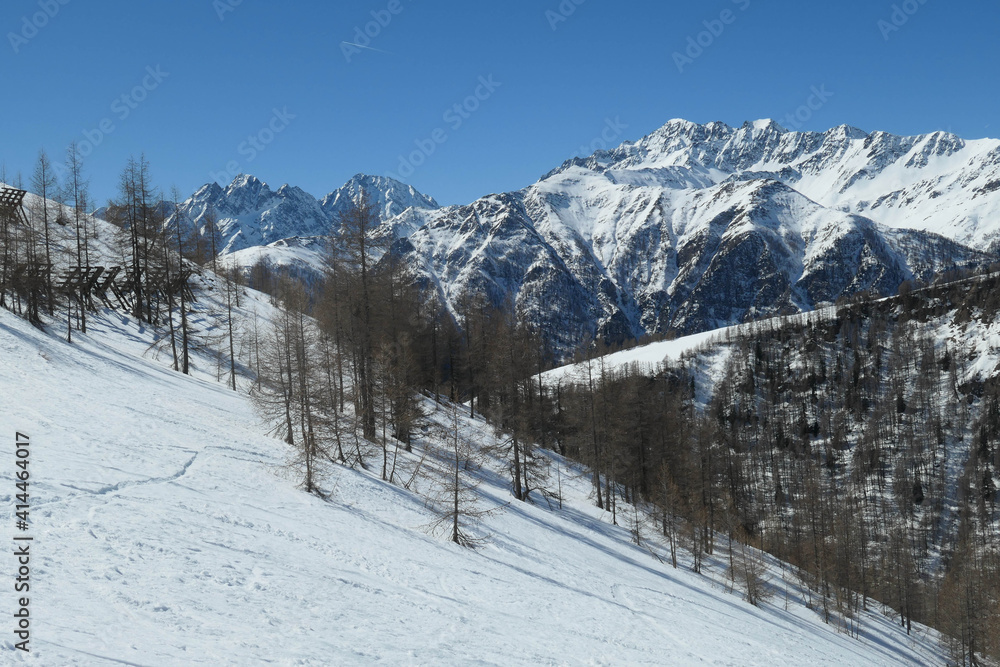 A beautiful and serene landscape of mountains covered with snow. Thick snow covers the slopes. Clear weather. Sharp slopes of the mountains covered with snow, with partially visible rocks.
