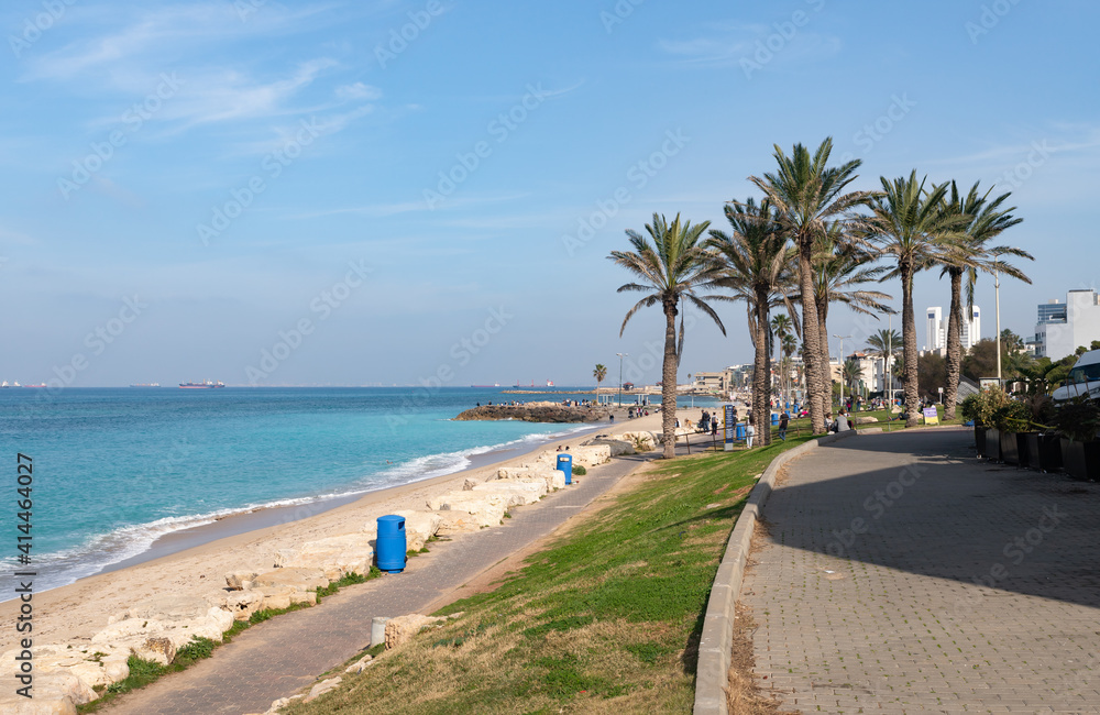 A few tourists and residents of the city walk along the embankment against the backdrop of the Mediterranean Sea in Haifa city, in northern Israel.