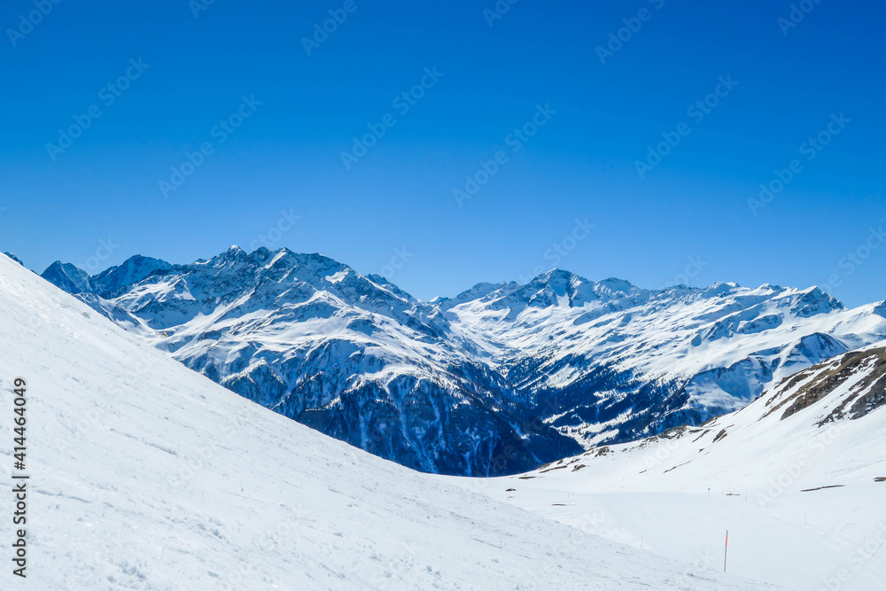 A beautiful and serene landscape of mountains covered with snow. Thick snow covers the slopes. Clear weather. Sharp slopes of the mountains covered with snow, with partially visible rocks. A beautiful and serene landscape of mountains covered with snow. Thick snow covers the slopes. Clear weather. Sharp slopes of the mountains covered with snow, with partially visible rocks.