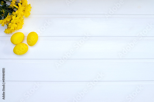 small yellow flowers and yellow Easter eggs in the upper left corner,spring and Easter card, top view, place for text
