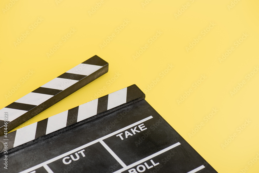 close up view of clapperboard on yellow background, cinema concept