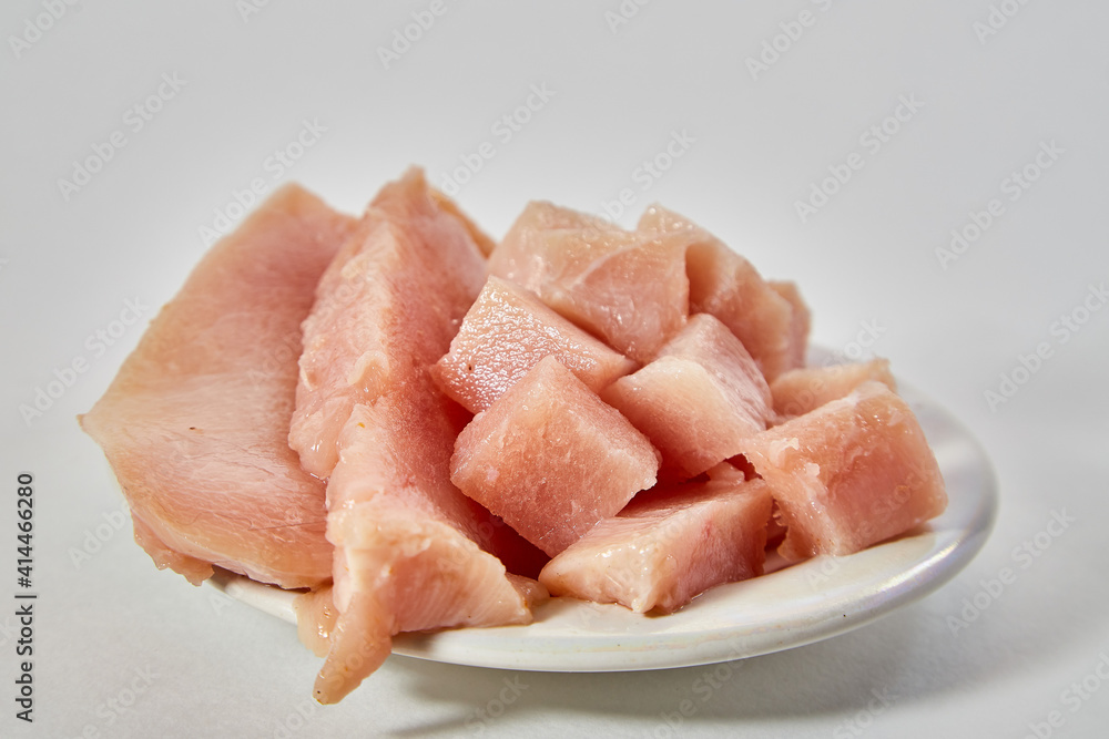 Pieces of Raw chicken meat on plate on white background Pieces of Raw chicken meat on plate on white background