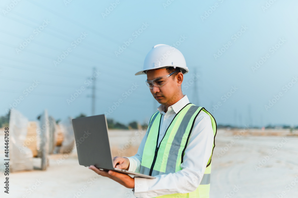 Professional Engineer wearing a helmet inspects a new project in a laptop. Professional Engineer wearing a helmet inspects a new project in a laptop.