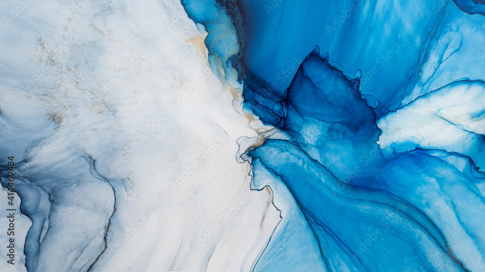 Naklejka premium Blue alcohol stains of paint with the addition of gold powder. Subtle waves of paint, abstract blue waves of the ocean, lines of marble. Liquid paints, gradient stains, painting.