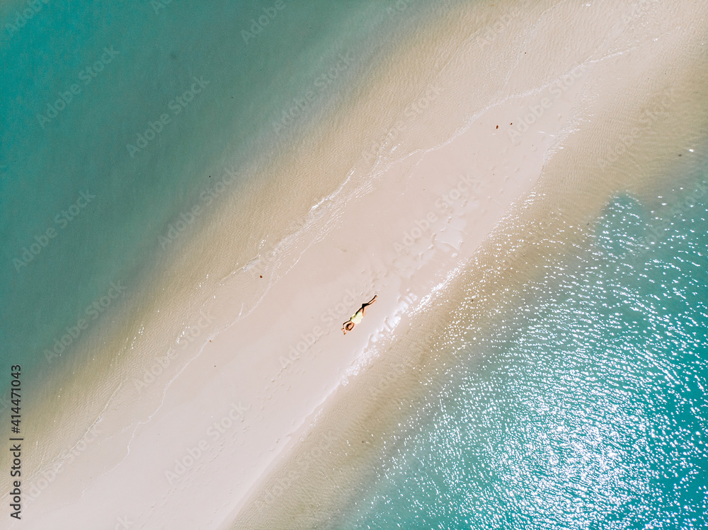 Slim girl in a yellow sexy tight bikini is sunbathing on the sand beach on Phuket island in Thailand. Top view aerial photo