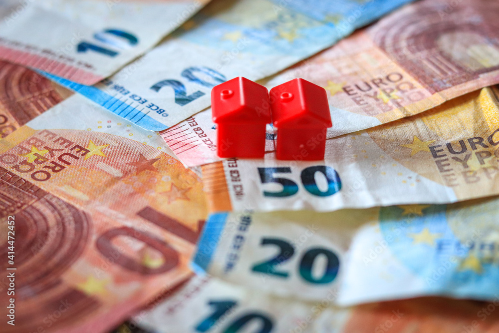 table covered with Euro banknotes with houses on top. Real estate investment concept	