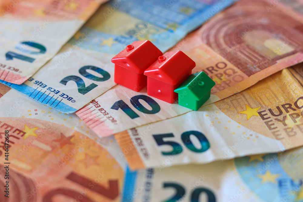 table covered with Euro banknotes with houses on top. Real estate investment concept	