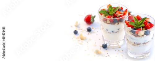 Banner. Two glasses of strawberry parfait made with fresh fruit, yogurt, blueberries, flax seeds and muesli, white background. Healthy Eating. Copy space